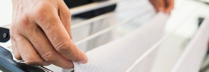 Eine Person hängt ein weißes Handtuch auf einen Wäscheständer.